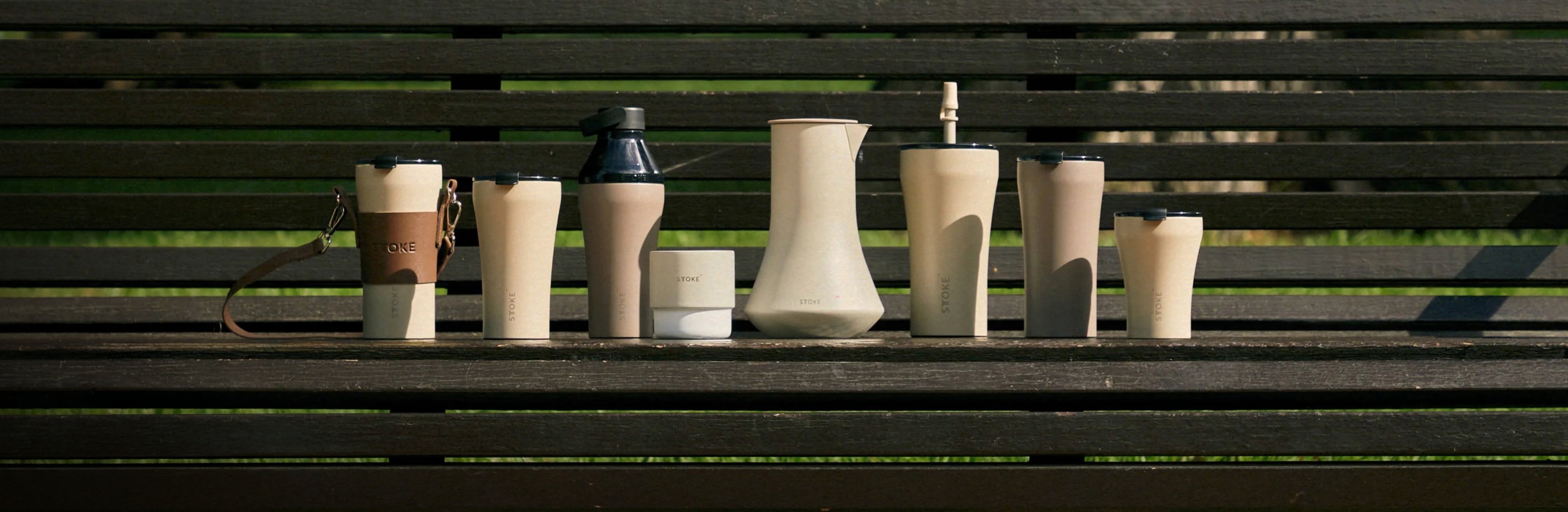 The STTOKE drinkware collection arranged on a sunlit park bench